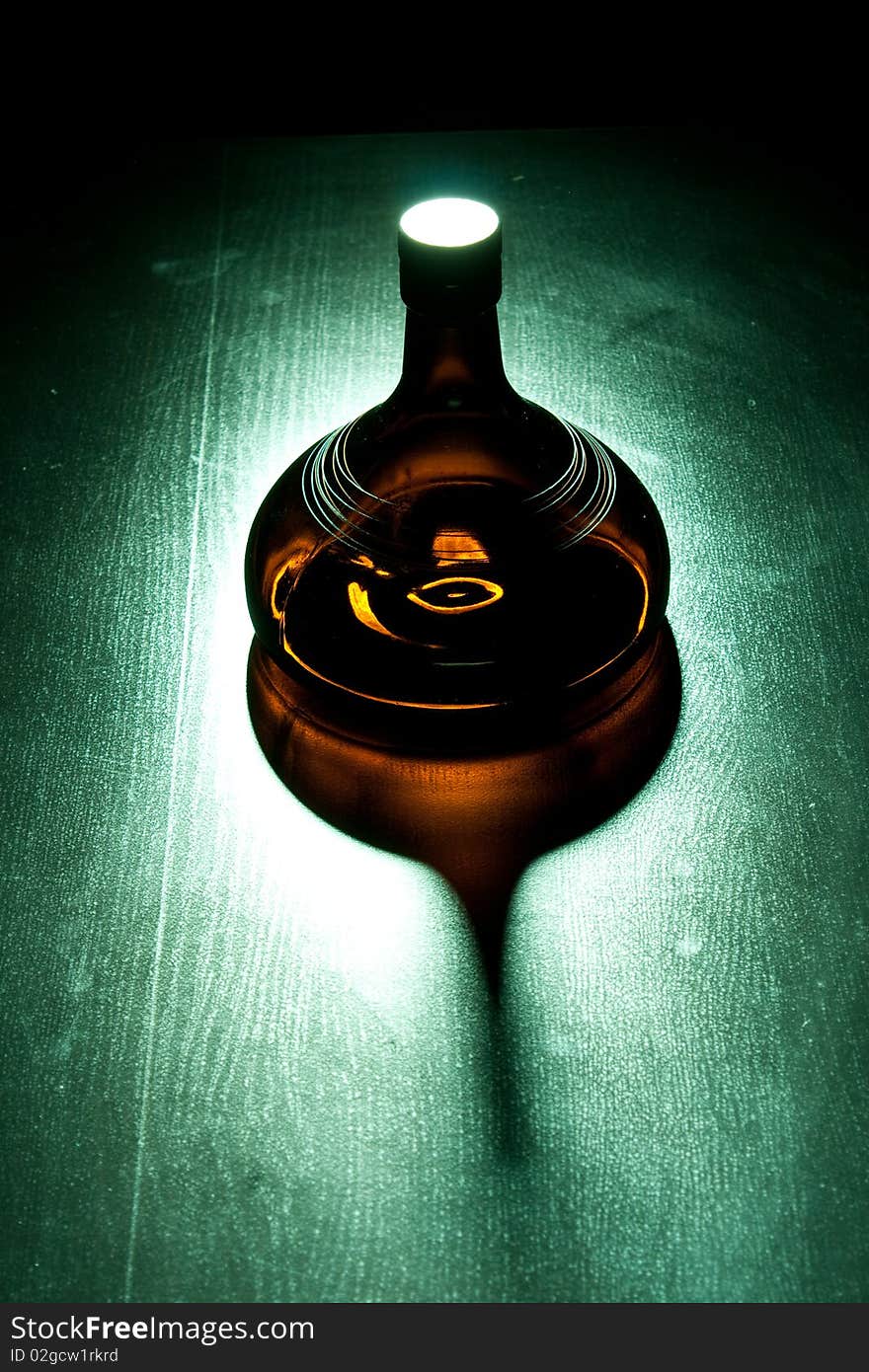 Amber bottle in green spotlight on the floor