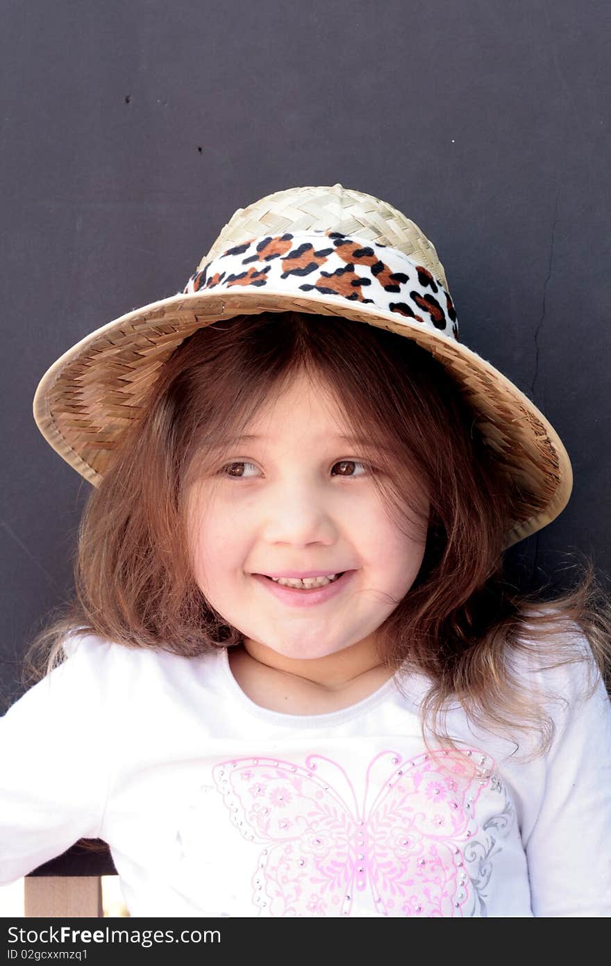 Pretty little girl smiling wearing a straw hat and black background. Pretty little girl smiling wearing a straw hat and black background