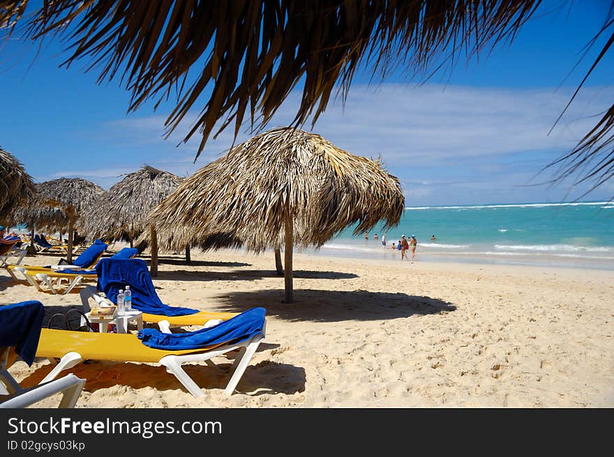 Many parasols made out of palm leafs on beach.