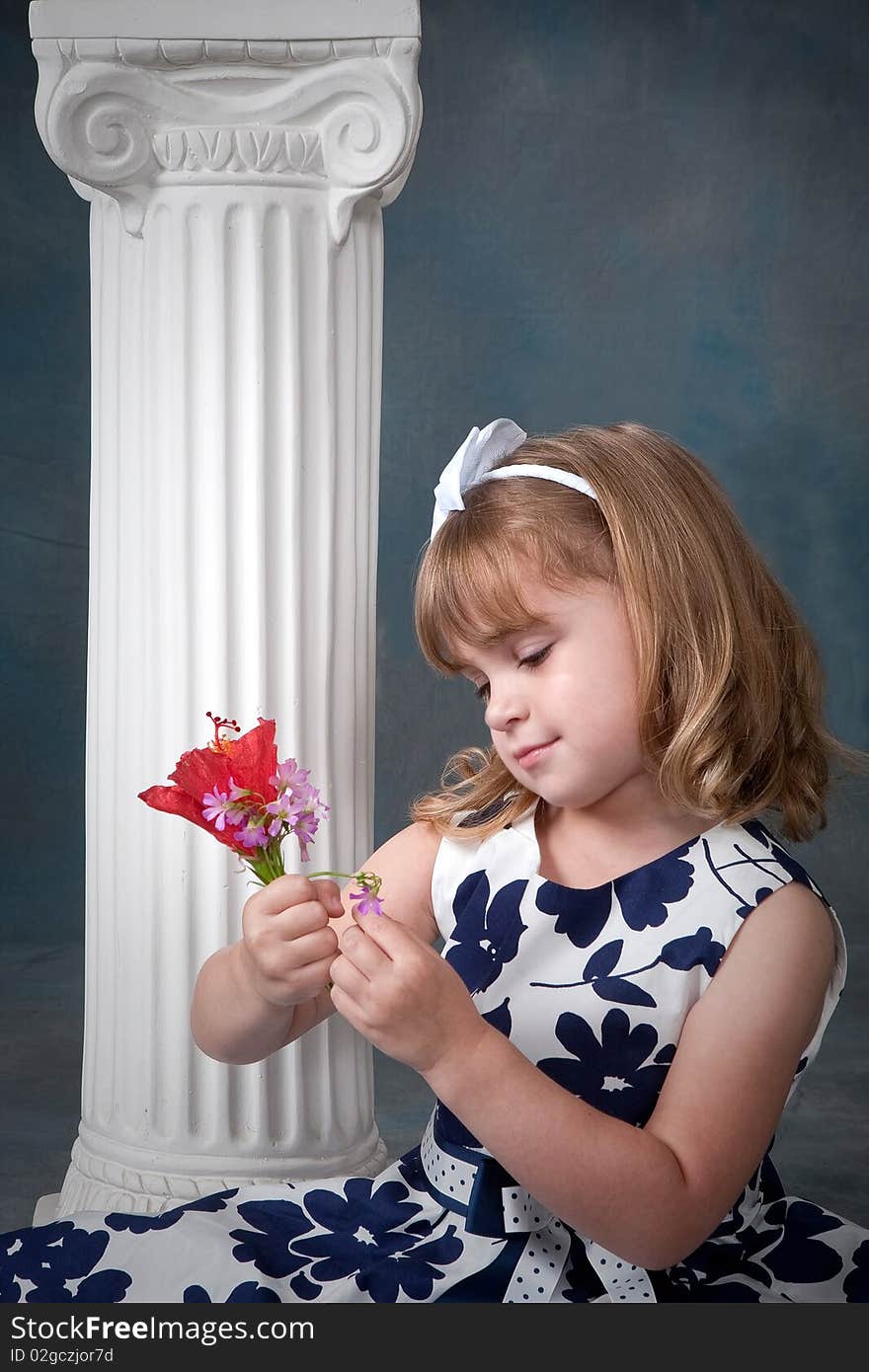 Pretty little girl with blond hair pulling petals off a flower. Pretty little girl with blond hair pulling petals off a flower.