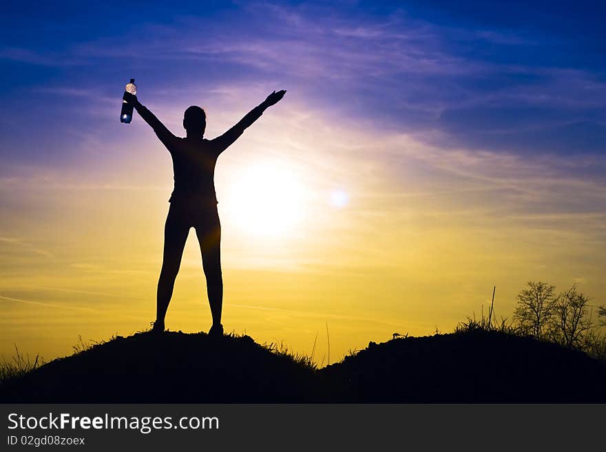 Athletic woman in the sunset happy in the hands of mineral water. Athletic woman in the sunset happy in the hands of mineral water.