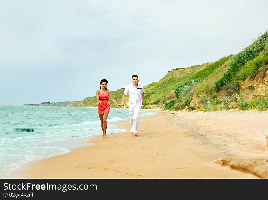 Lovely happy couple running along the beach