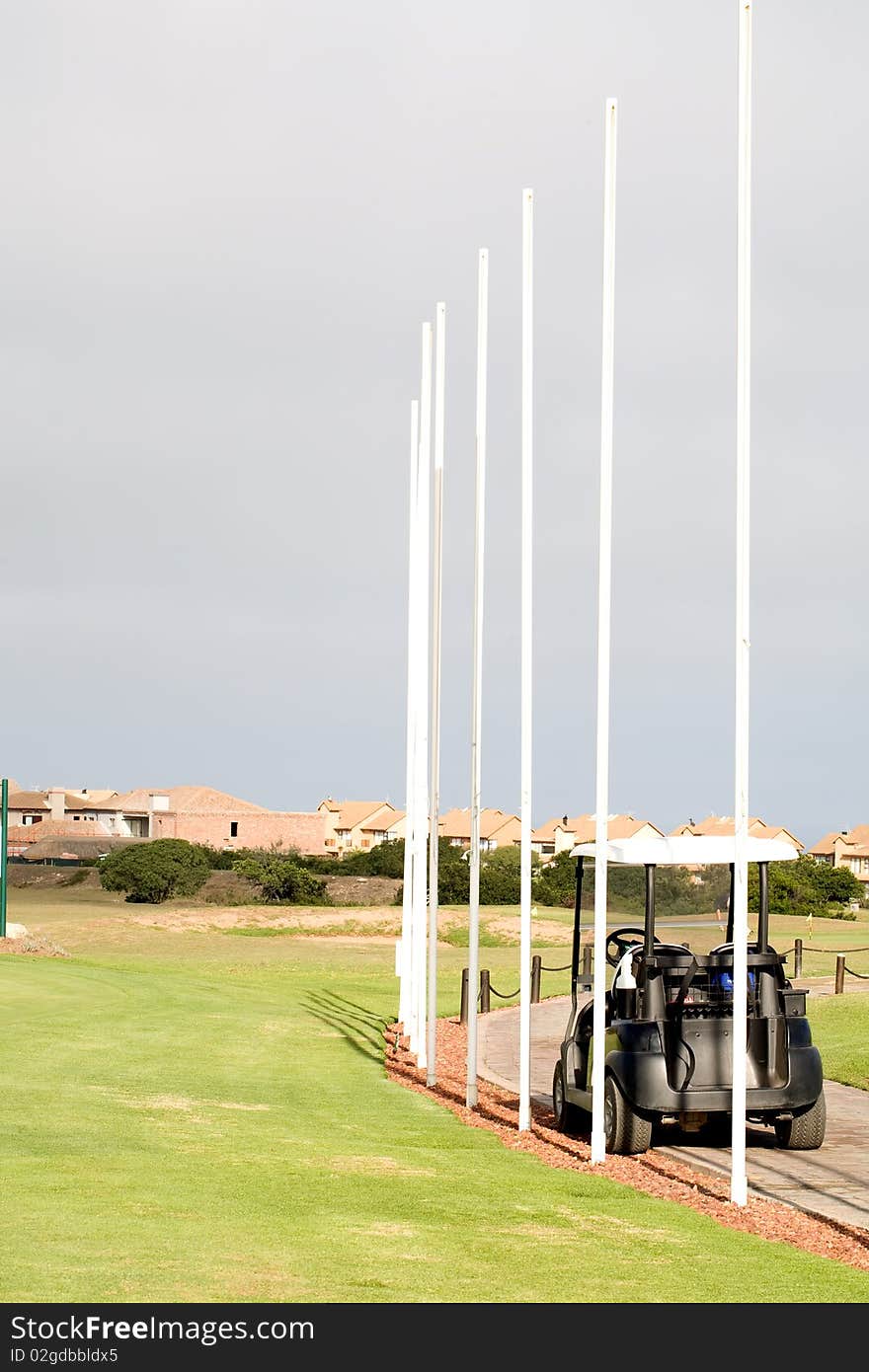 Flag poles on a golf course with a golf car standing by.