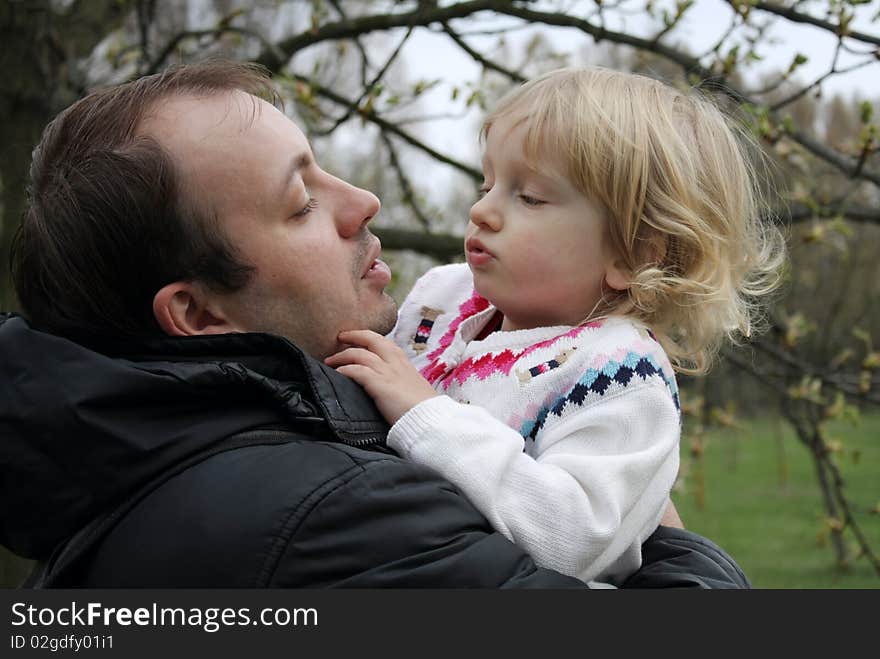 Dad keeps daughter in his arms for a walk in the park. Dad keeps daughter in his arms for a walk in the park