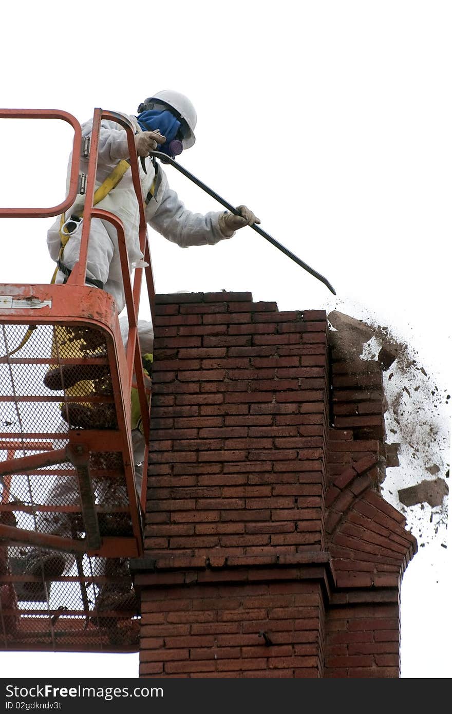 Frank (model release) wearing protective clothing and hardhat, during demolition of an old 1888 brick building by hand because of the integrity of the structure corner could collapse. Heavy Construction with bucket lift. Frank (model release) wearing protective clothing and hardhat, during demolition of an old 1888 brick building by hand because of the integrity of the structure corner could collapse. Heavy Construction with bucket lift.