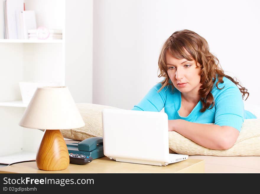 Beautiful woman sitting on sofa and using laptop