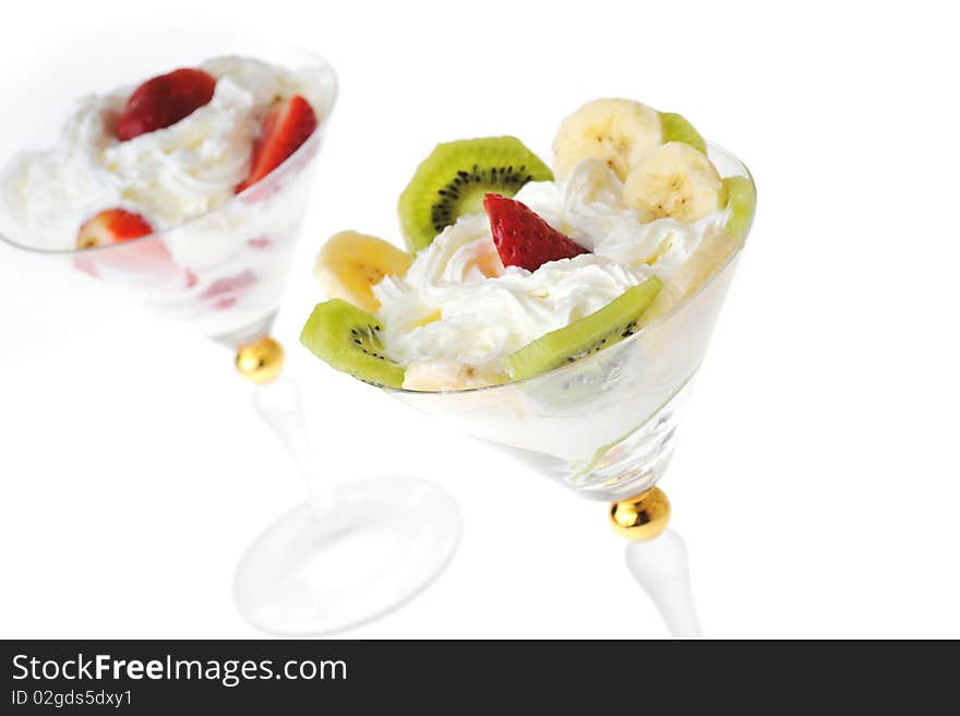 Fresh chopped strawberries, kiwi and banana with whipped cream in glasswares. Fresh chopped strawberries, kiwi and banana with whipped cream in glasswares