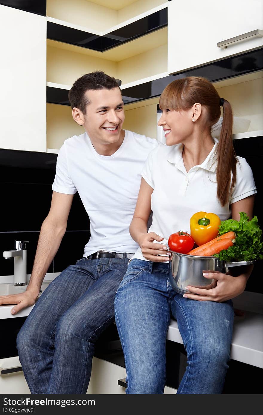 Smiling couple with capacity with vegetables on kitchen. Smiling couple with capacity with vegetables on kitchen