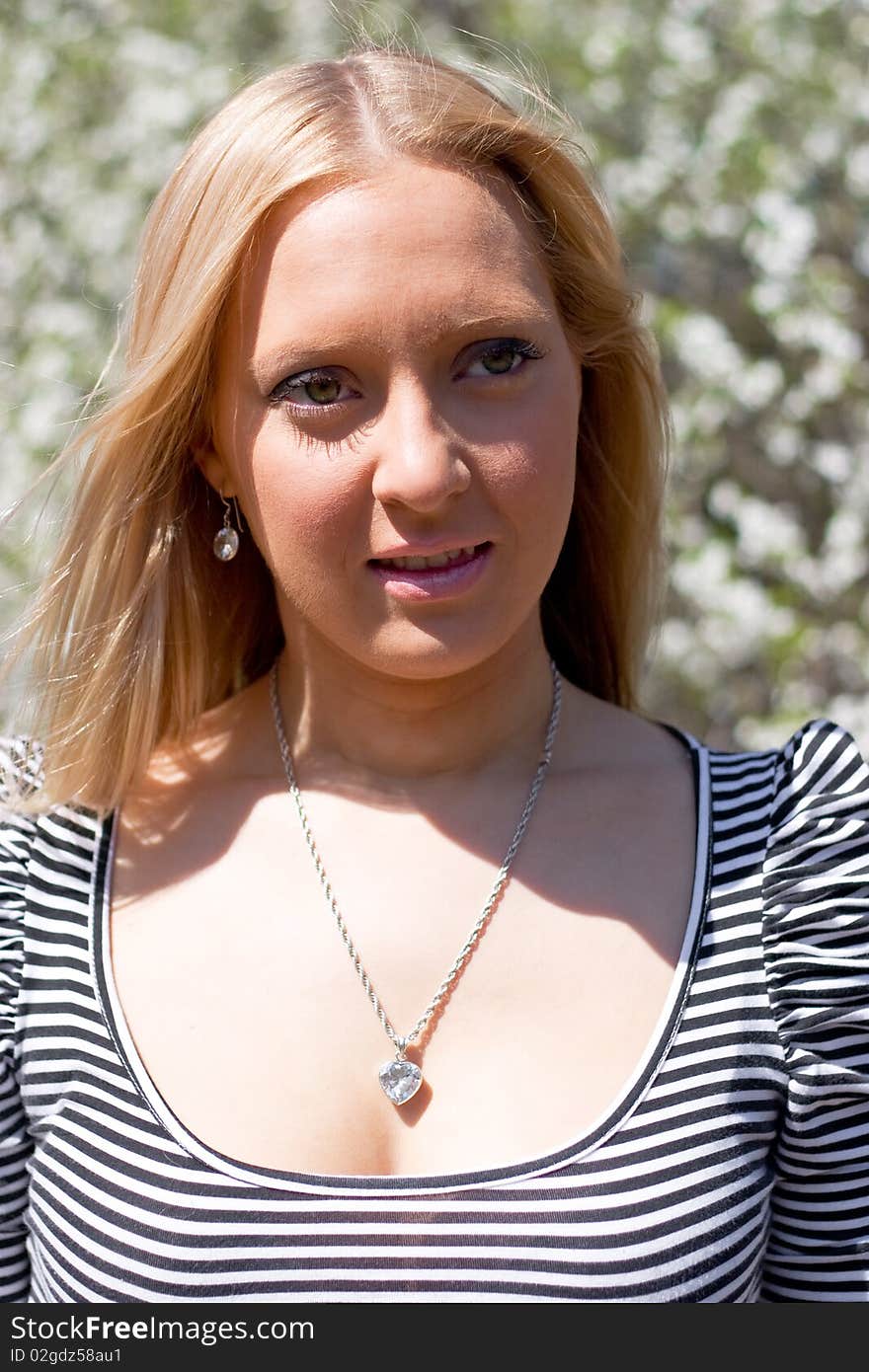 Blond girl in front of blossomed tree on early spring