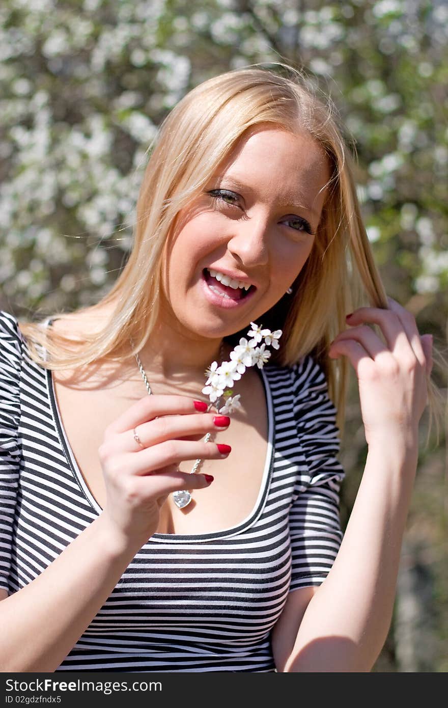 Blond girl in front of blossomed tree on early spring