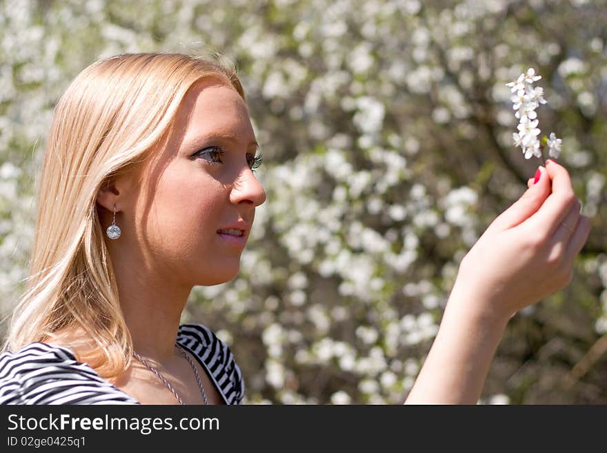 Blond girl in front of blossomed tree on early spring