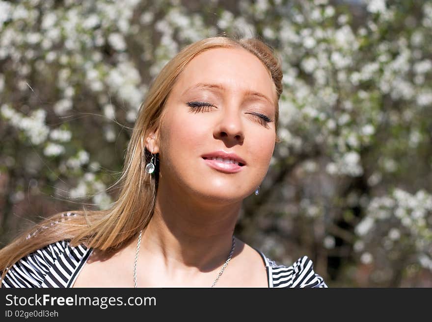 Blond girl in front of blossomed tree on early spring