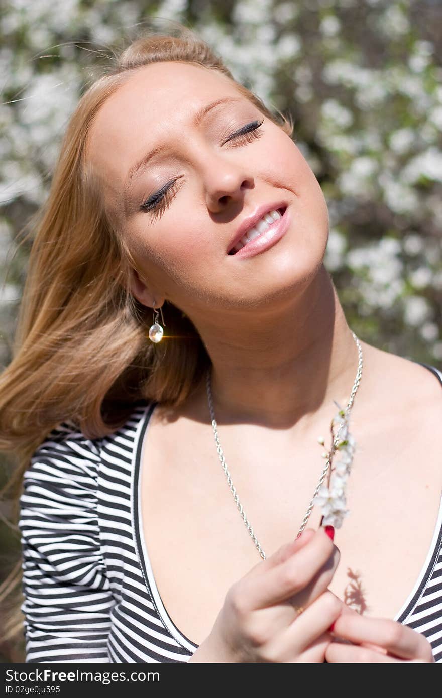 Blond girl in front of blossomed tree on early spring