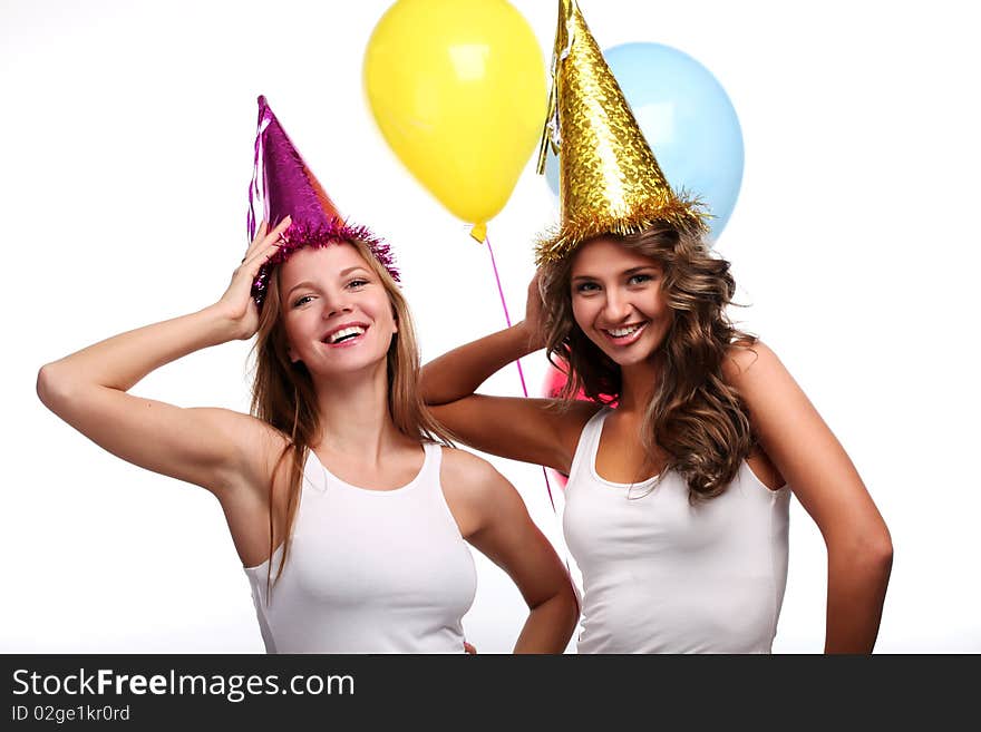 Two young girlfriends in holiday caps with color balloons. Two young girlfriends in holiday caps with color balloons