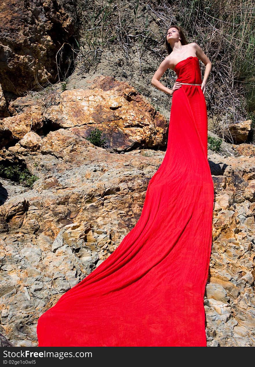 Woman in red dress from material and rocks