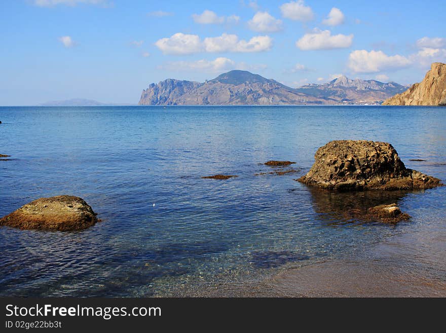 Seascape - stone, sand, clear water, and in the distance an old volcano. Seascape - stone, sand, clear water, and in the distance an old volcano