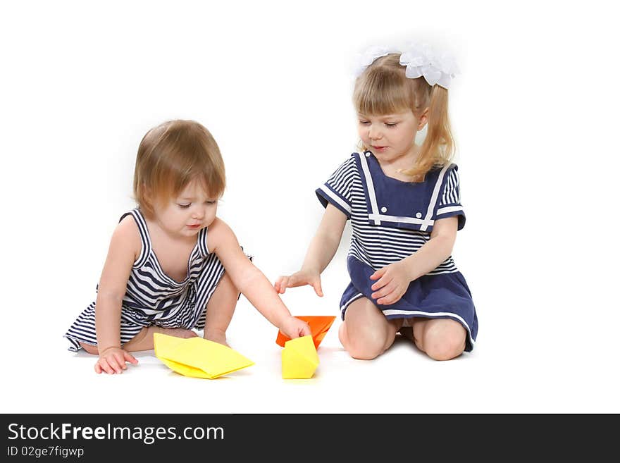 Two girls playing with paper ships over white