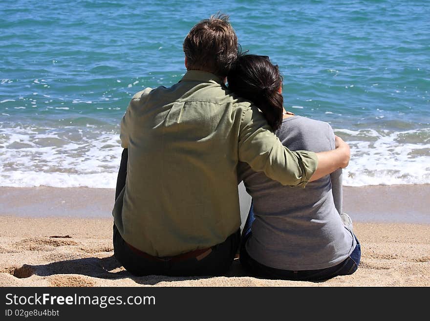 A young couple sitting on the beach in spring