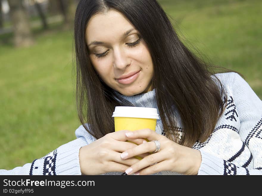 Beautiful girl in a park drinking coffee