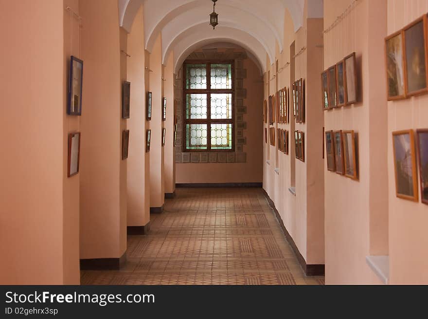 Ancient castle arcade with pictures on the walls and stained-glass window. Ancient castle arcade with pictures on the walls and stained-glass window