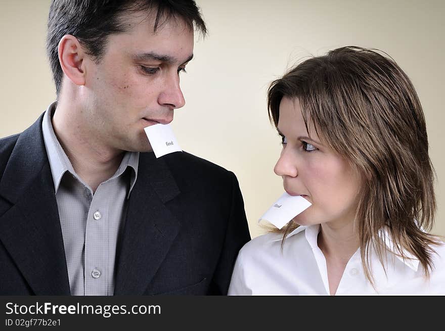 White man and woman holding in mouth papers with fired words. White man and woman holding in mouth papers with fired words