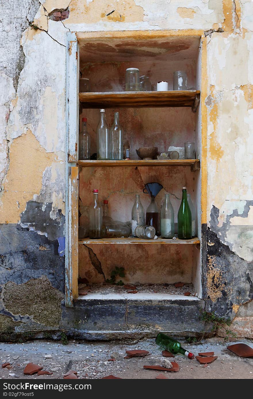 An old broken shelf unit with glass bottles. An old broken shelf unit with glass bottles