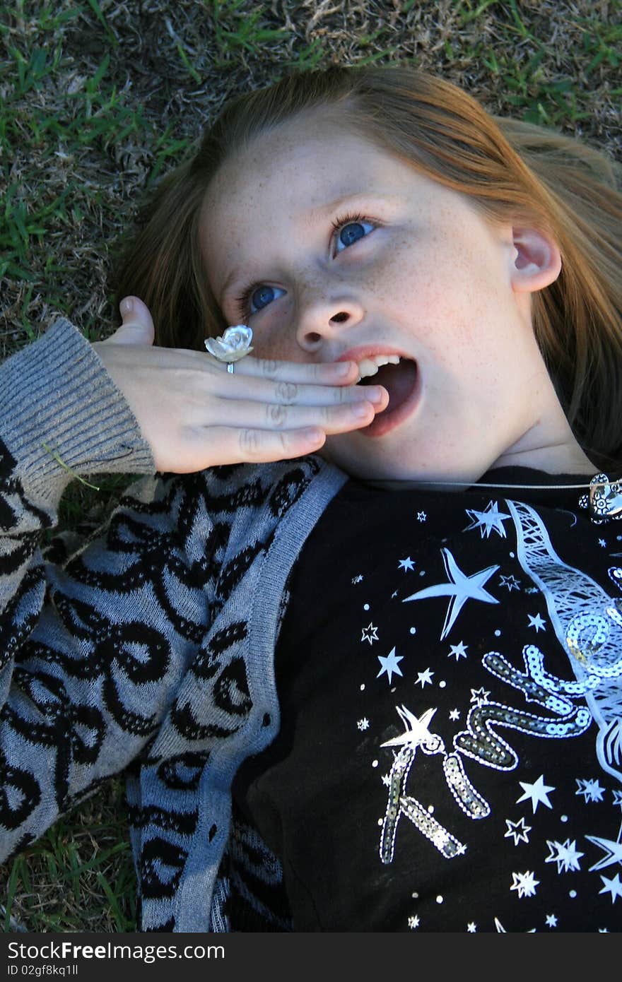 A beautiful white caucasian girl child with a shocked expression on her face holding her hand to her mouth. A beautiful white caucasian girl child with a shocked expression on her face holding her hand to her mouth