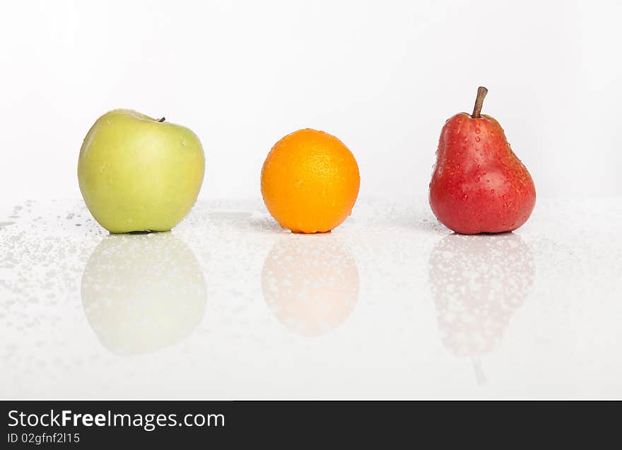 Apple orange pear row with water drops