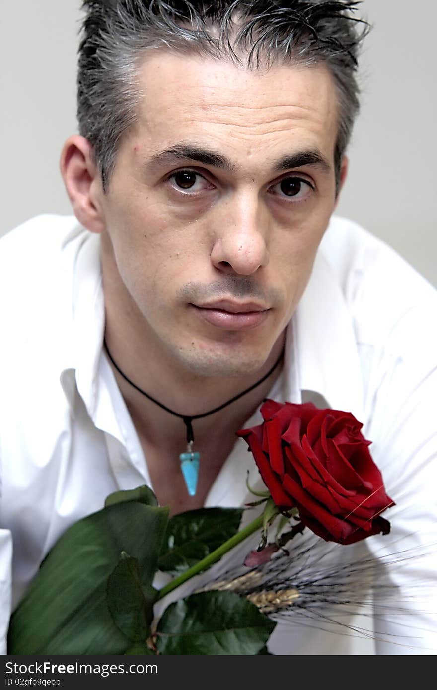 Portrait of a man with a white shirt and a red rose in hand. Portrait of a man with a white shirt and a red rose in hand