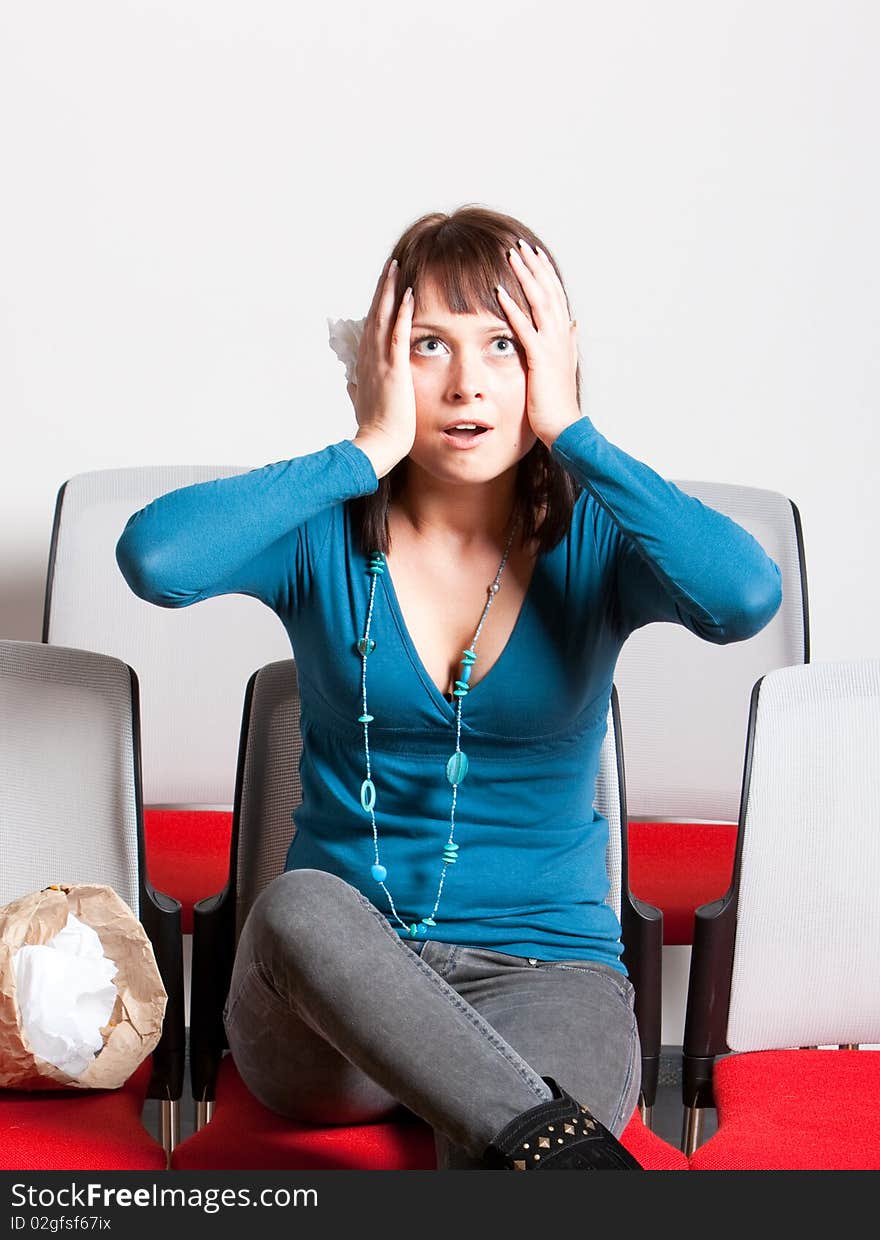 Scared young woman sitting and holding her hands on head with open mouth, vertical shot. Scared young woman sitting and holding her hands on head with open mouth, vertical shot