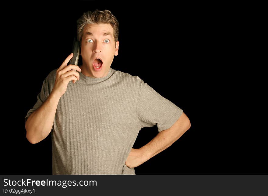 Man using a phone looking surprised on a black background