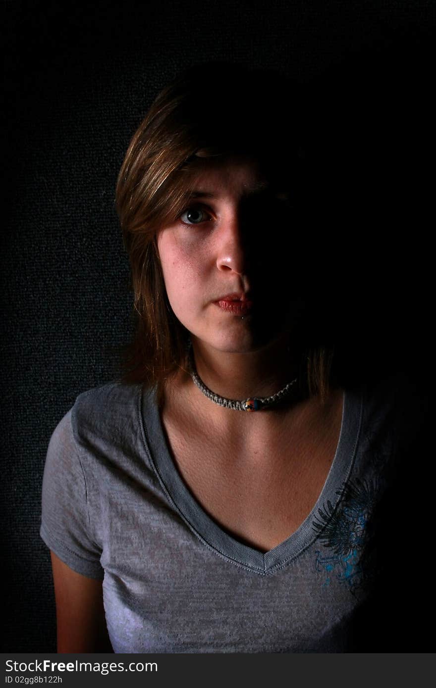 A young lady appearing sad in a low key shot. A young lady appearing sad in a low key shot