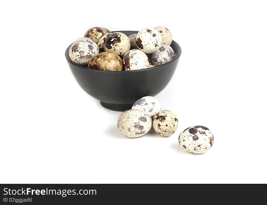 Quail eggs in a bowl of black on a white background