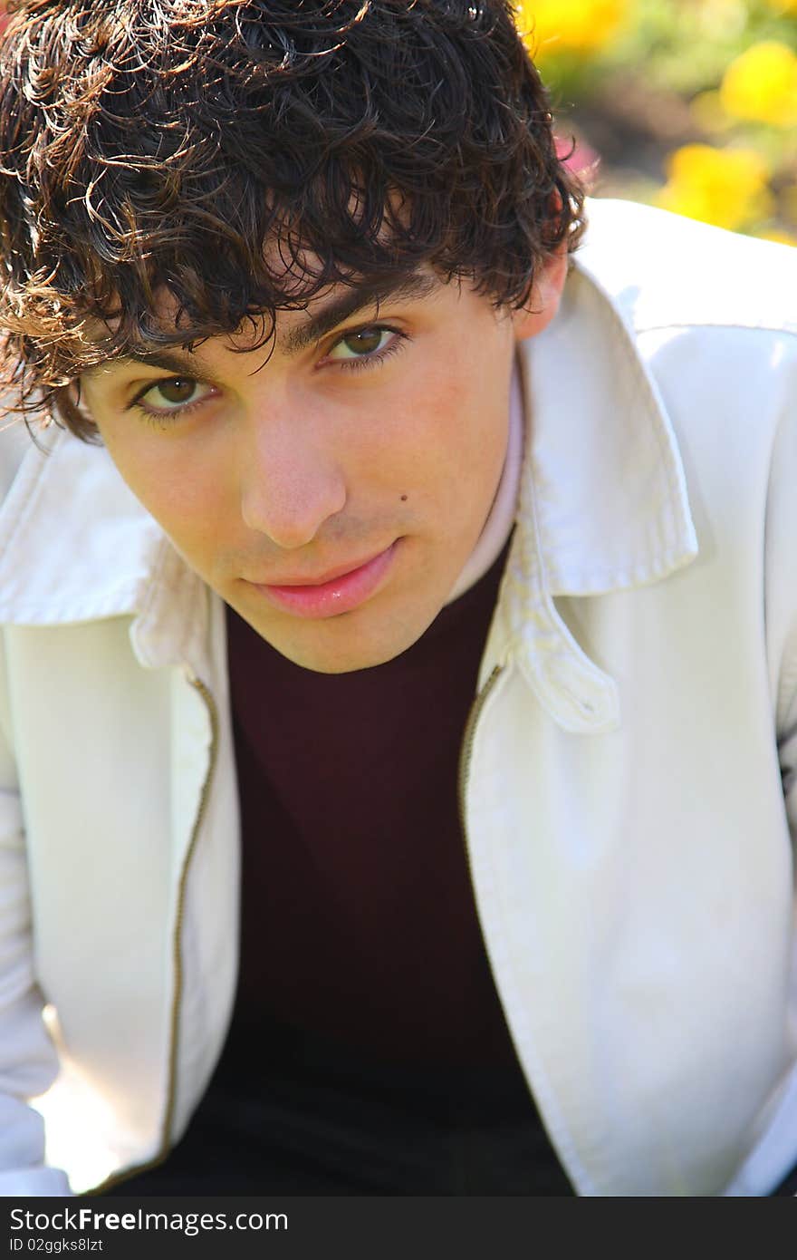 Curly haired young adult man in white, outdoor portrait