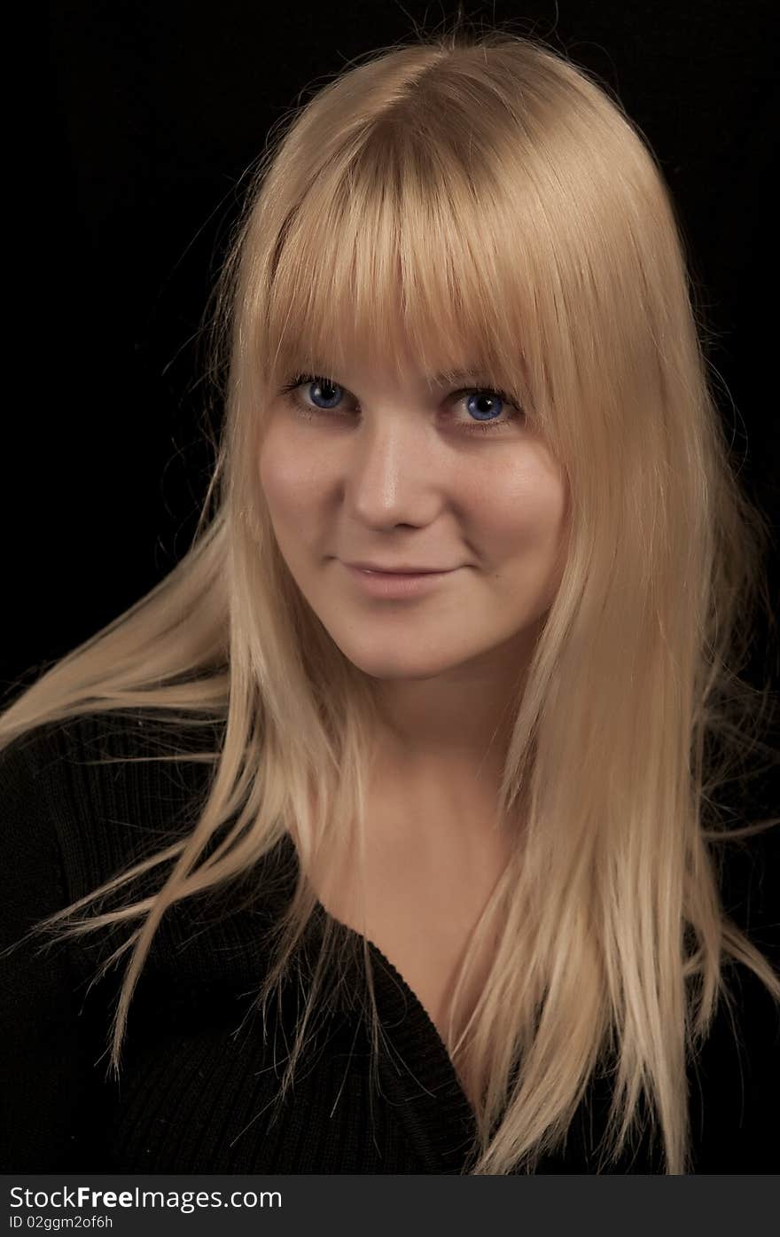 Young blond girl in black background. Young blond girl in black background