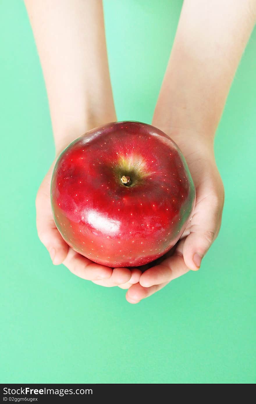 Child holding a red apple on green background vert