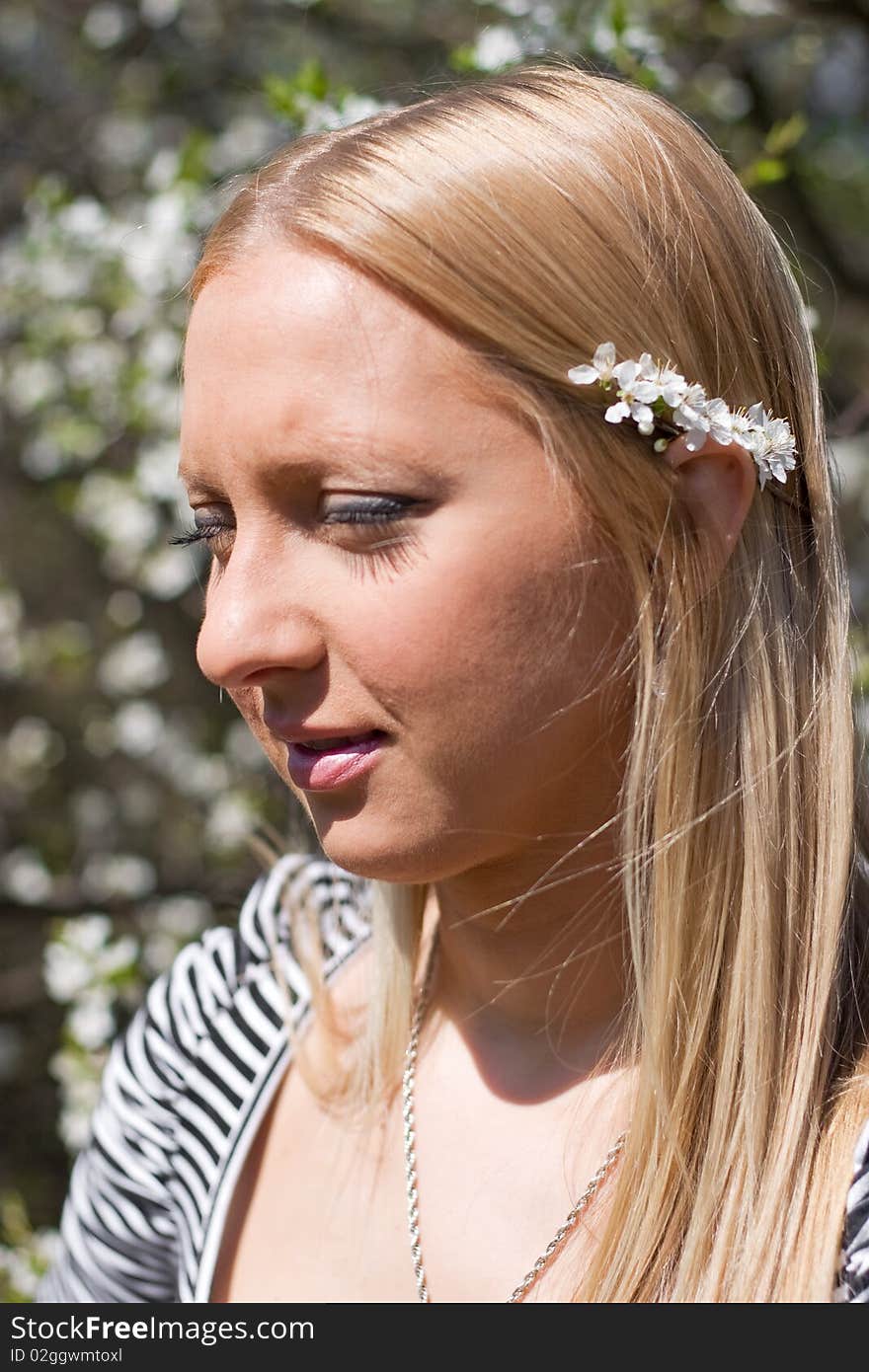 Blond girl in front of blossomed tree on early spring