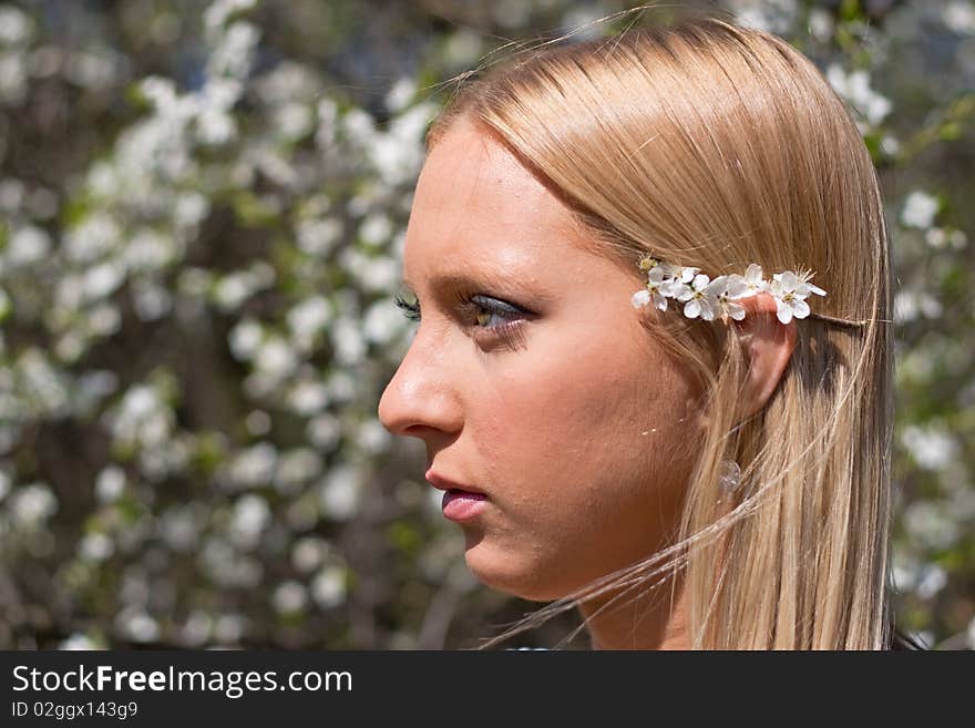 Blond girl in front of blossomed tree on early spring