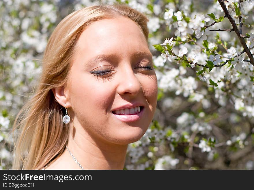 Blond girl in front of blossomed tree on early spring