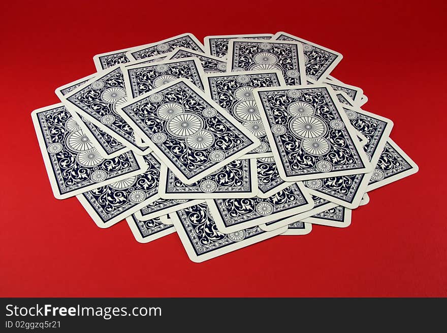 The scattered dark blue playing cards on a red background. The scattered dark blue playing cards on a red background