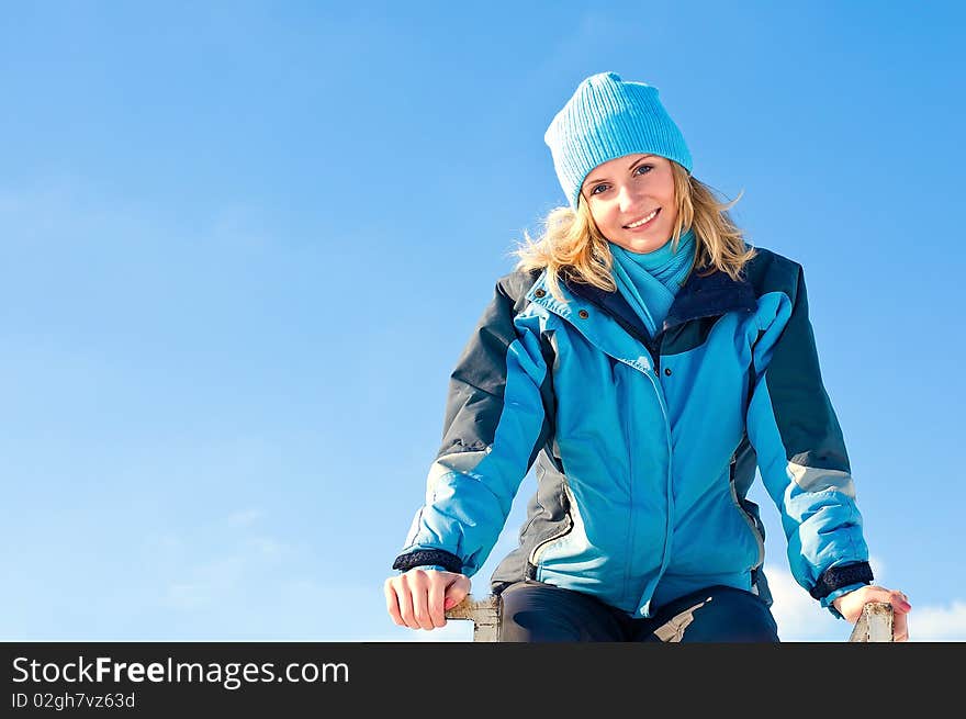 The young girl  on a background of the sky looks in a distance in the winter