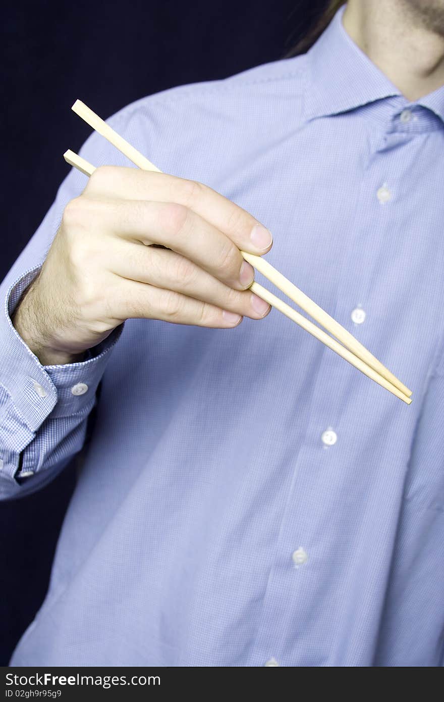 A young man in a blue shirt in his hand, wooden sticks for land. A young man in a blue shirt in his hand, wooden sticks for land