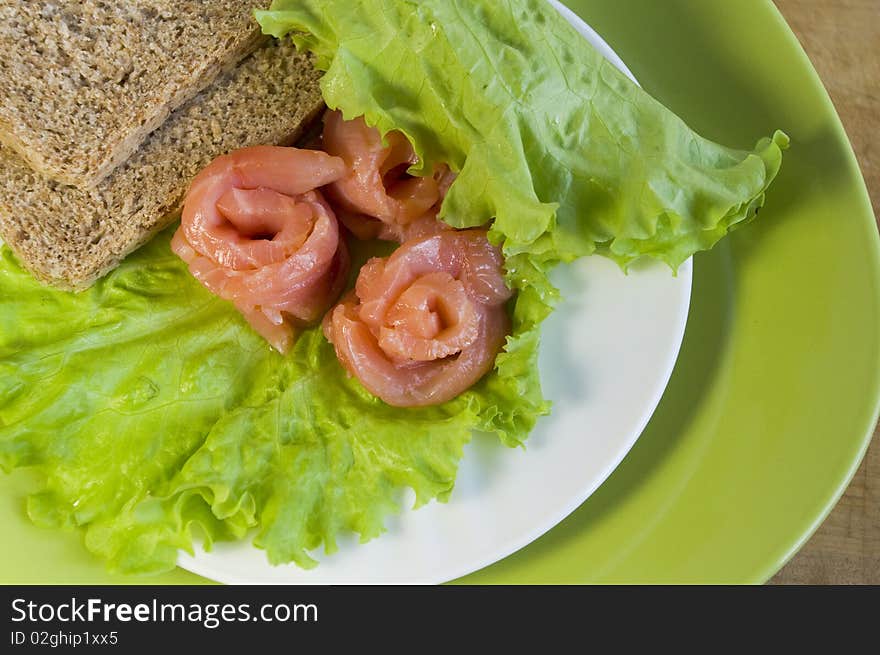 Slices of bread and three slices of a salmon on a white plate. Slices of bread and three slices of a salmon on a white plate