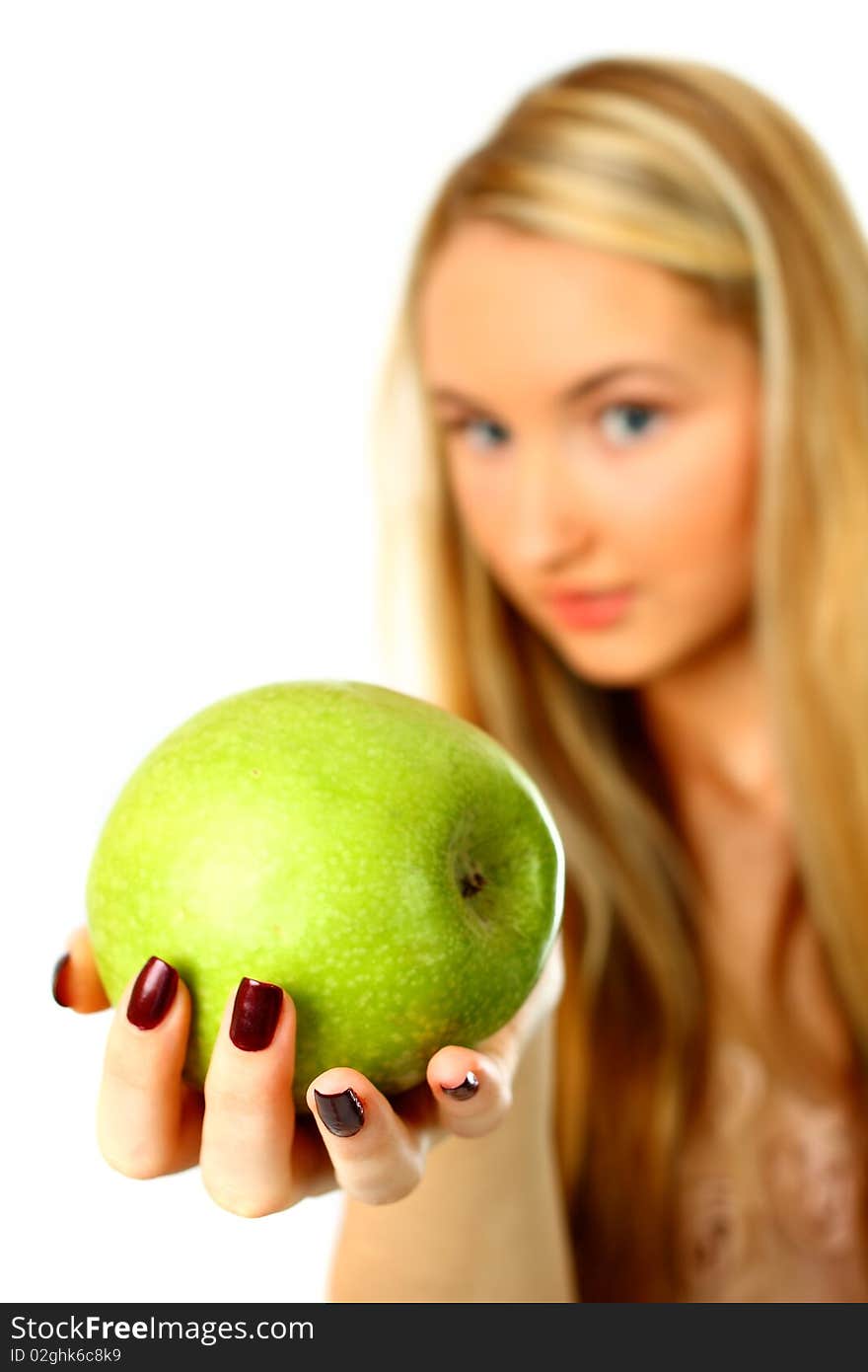 Young woman holding an apple into the camera - focus on apple. Young woman holding an apple into the camera - focus on apple