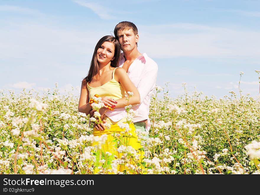 Young lovely couple in a spring field of flowers