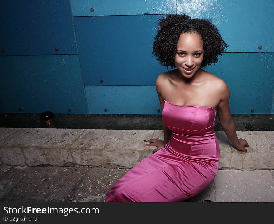 Attractive black woman sitting in a pink dress. Attractive black woman sitting in a pink dress