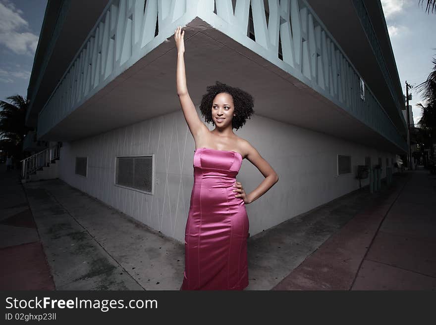 Young woman posing by a building corner