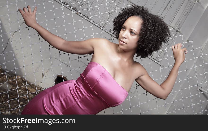 Young woman posing by a fence