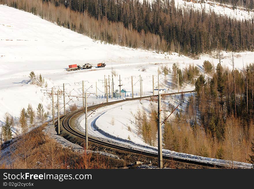 The railway in the winter bent between snow mountains