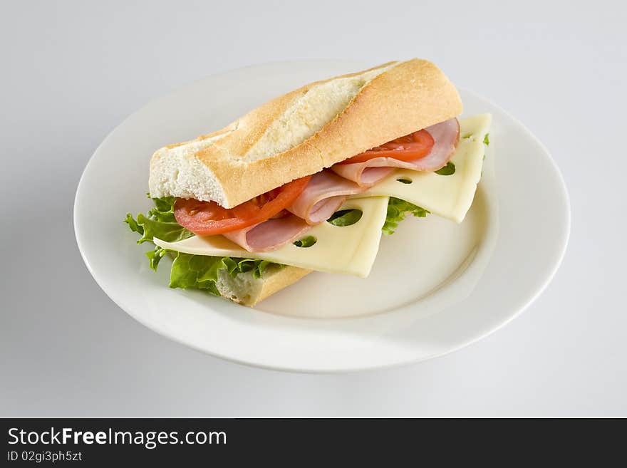 Ham and Swiss cheese baguette on white plate